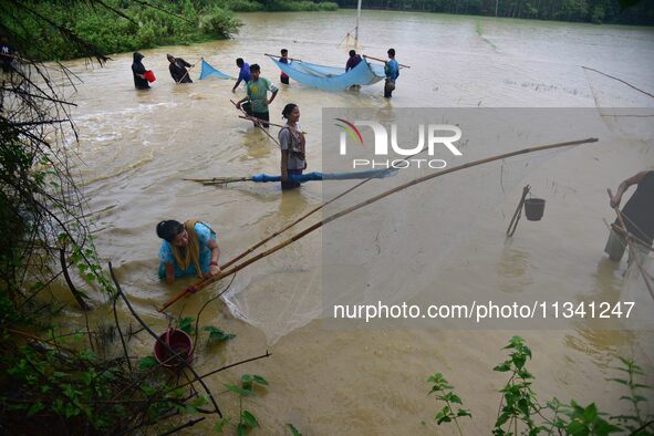 People are fishing on flood water following rains in Changchaki village in Nagaon District of Assam, India, on June 18, 2024. 