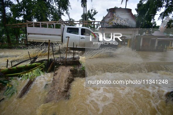 A vehicle is crossing a flooded road following rains in Changchaki village in Nagaon District of Assam, India, on June 18, 2024. 