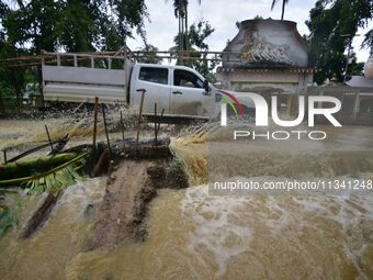 A vehicle is crossing a flooded road following rains in Changchaki village in Nagaon District of Assam, India, on June 18, 2024. (