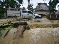 A vehicle is crossing a flooded road following rains in Changchaki village in Nagaon District of Assam, India, on June 18, 2024. (