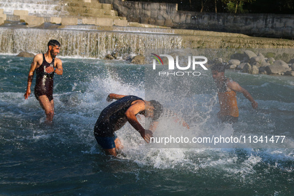 Men are taking a bath in a stream on a sunny day in Kangan, about 70kms from Srinagar, on June 18, 2024. 