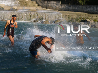 Men are taking a bath in a stream on a sunny day in Kangan, about 70kms from Srinagar, on June 18, 2024. (