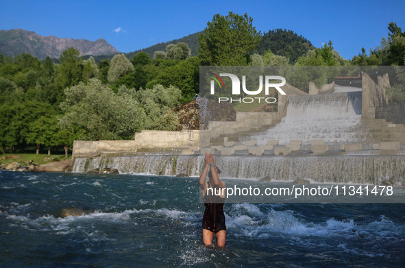 A man is taking a bath in a stream on a sunny day in Kangan, about 70kms from Srinagar, on June 18, 2024. 