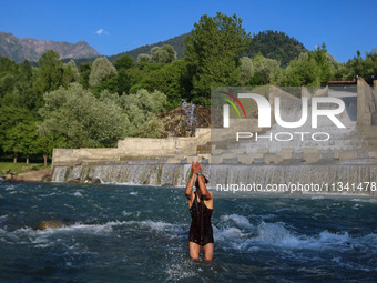 A man is taking a bath in a stream on a sunny day in Kangan, about 70kms from Srinagar, on June 18, 2024. (