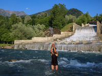 A man is taking a bath in a stream on a sunny day in Kangan, about 70kms from Srinagar, on June 18, 2024. (