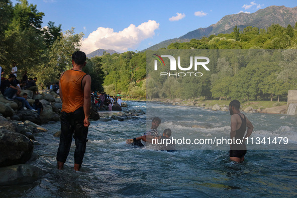 Men are taking a bath in a stream on a sunny day in Kangan, about 70kms from Srinagar, on June 18, 2024. 