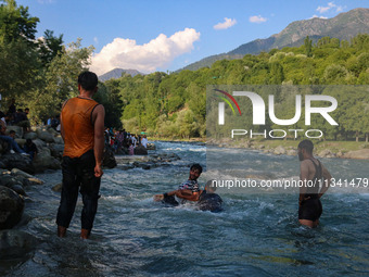 Men are taking a bath in a stream on a sunny day in Kangan, about 70kms from Srinagar, on June 18, 2024. (