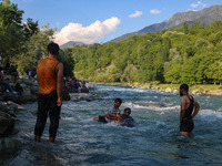 Men are taking a bath in a stream on a sunny day in Kangan, about 70kms from Srinagar, on June 18, 2024. (