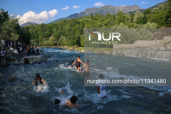 Men are taking a bath in a stream on a sunny day in Kangan, about 70kms from Srinagar, on June 18, 2024. 