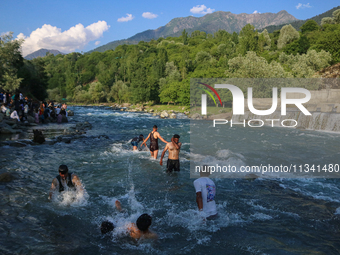 Men are taking a bath in a stream on a sunny day in Kangan, about 70kms from Srinagar, on June 18, 2024. (