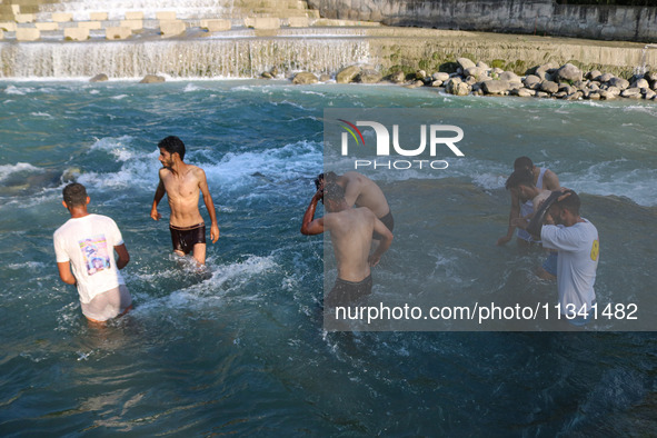 Men are taking a bath in a stream on a sunny day in Kangan, about 70kms from Srinagar, on June 18, 2024. 