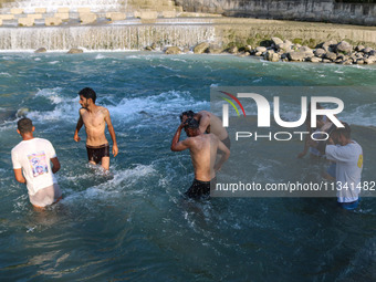 Men are taking a bath in a stream on a sunny day in Kangan, about 70kms from Srinagar, on June 18, 2024. (