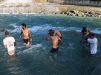 Men are taking a bath in a stream on a sunny day in Kangan, about 70kms from Srinagar, on June 18, 2024. (