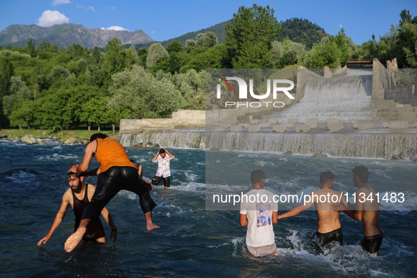 Men are taking a bath in a stream on a sunny day in Kangan, about 70kms from Srinagar, on June 18, 2024. 