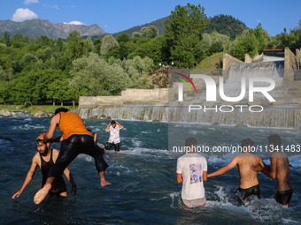 Men are taking a bath in a stream on a sunny day in Kangan, about 70kms from Srinagar, on June 18, 2024. (