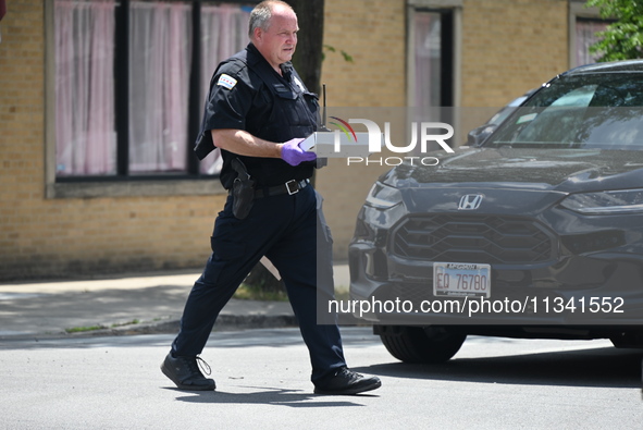 An evidence tech is carrying an evidence box with the recovered weapon at the scene on W. Belmont Av. where the vehicles are being recovered...