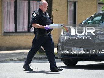 An evidence tech is carrying an evidence box with the recovered weapon at the scene on W. Belmont Av. where the vehicles are being recovered...