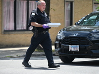 An evidence tech is carrying an evidence box with the recovered weapon at the scene on W. Belmont Av. where the vehicles are being recovered...