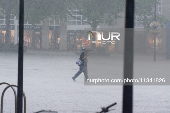 A woman is struggling with her umbrella during the storm in Dortmund, Germany, on June 18, 2024. 