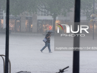 A woman is struggling with her umbrella during the storm in Dortmund, Germany, on June 18, 2024. (