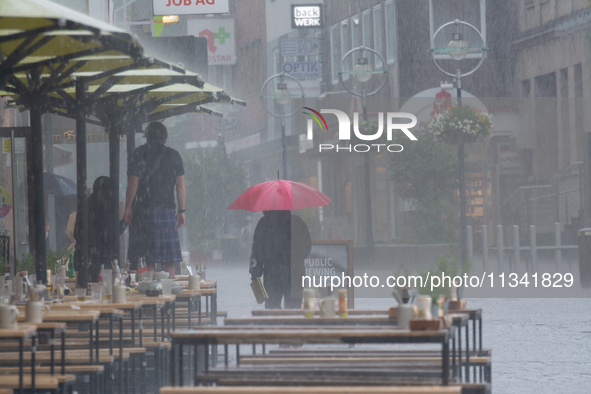 A woman is struggling with her umbrella during the storm in Dortmund, Germany, on June 18, 2024. 