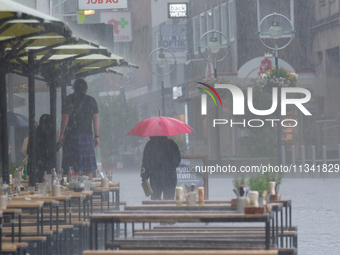 A woman is struggling with her umbrella during the storm in Dortmund, Germany, on June 18, 2024. (