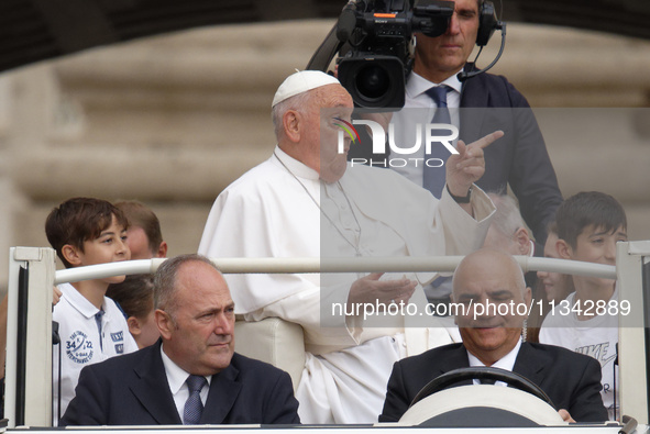 Pope Francis is gesturing as he arrives to lead the weekly general audience in Saint Peter's Square, Vatican City, on June 19, 2024. 