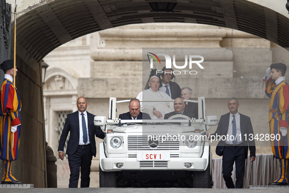 Pope Francis is waving as he is arriving to lead the weekly general audience in Saint Peter's Square, Vatican City, on June 19, 2024. 