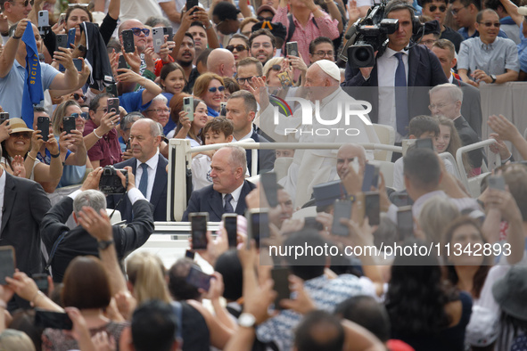 Pope Francis is waving as he is arriving to lead the weekly general audience in Saint Peter's Square, Vatican City, on June 19, 2024. 