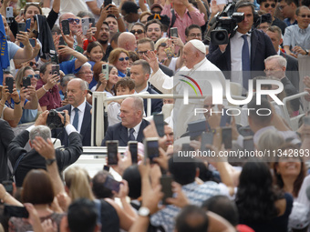 Pope Francis is waving as he is arriving to lead the weekly general audience in Saint Peter's Square, Vatican City, on June 19, 2024. (