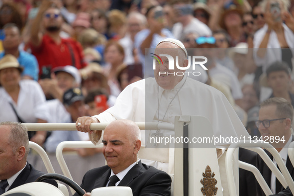 Pope Francis is waving as he is arriving to lead the weekly general audience in Saint Peter's Square, Vatican City, on June 19, 2024. 