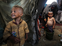 A Palestinian woman is washing a child inside her tent at a camp for displaced people during a hot day in Deir al-Balah, in the central Gaza...