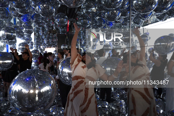 A woman is bouncing silver Mylar balloons at ''Affinity'' at Summit One Vanderbilt observation deck in New York, U.S., on Thursday, June 18,...