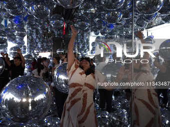 A woman is bouncing silver Mylar balloons at ''Affinity'' at Summit One Vanderbilt observation deck in New York, U.S., on Thursday, June 18,...