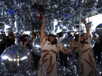 A woman is bouncing silver Mylar balloons at ''Affinity'' at Summit One Vanderbilt observation deck in New York, U.S., on Thursday, June 18,...