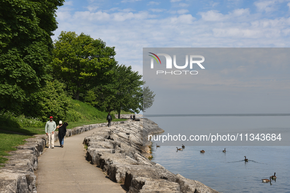 People are walking along a waterfront trail by Lake Ontario at Queen's Royal Park in Niagara-on-the-Lake, Ontario, Canada, on June 12, 2024....