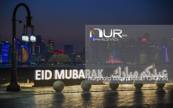 The Doha skyline is being seen behind an installation marking the Eid al-Adha celebrations 'EID MUBARAK' at Old Doha Port in Doha, Qatar, on...