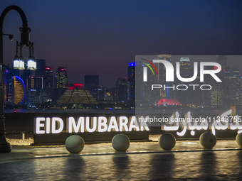 The Doha skyline is being seen behind an installation marking the Eid al-Adha celebrations 'EID MUBARAK' at Old Doha Port in Doha, Qatar, on...