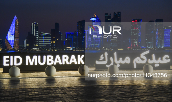 The Doha skyline is being seen behind an installation marking the Eid al-Adha celebrations 'EID MUBARAK' at Old Doha Port in Doha, Qatar, on...