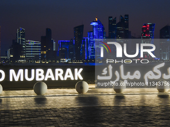 The Doha skyline is being seen behind an installation marking the Eid al-Adha celebrations 'EID MUBARAK' at Old Doha Port in Doha, Qatar, on...