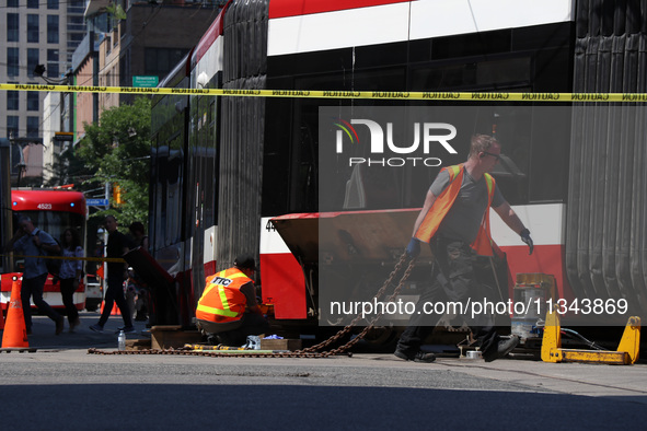 TTC workers are fixing a streetcar as it is stuck at King Street East and Church Street in Toronto, Canada, on June 19, 2024. 