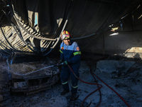 A firefighter is dropping water to extinguish a fire inside an industrial building in Koropi near Athens, Greece, on June 19, 2024. (