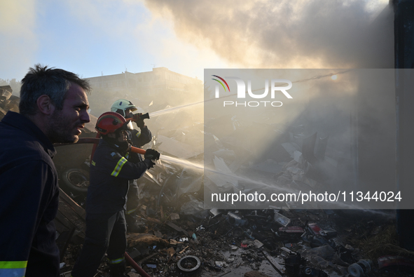 Firefighters are dropping water to extinguish a fire inside a container in Koropi near Athens, Greece, on June 19, 2024. 