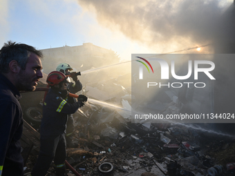 Firefighters are dropping water to extinguish a fire inside a container in Koropi near Athens, Greece, on June 19, 2024. (