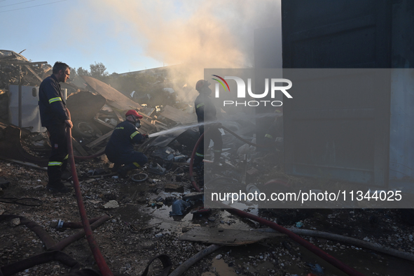 Firefighters are dropping water to extinguish a fire inside a container in Koropi near Athens, Greece, on June 19, 2024. 