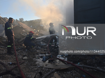 Firefighters are dropping water to extinguish a fire inside a container in Koropi near Athens, Greece, on June 19, 2024. (