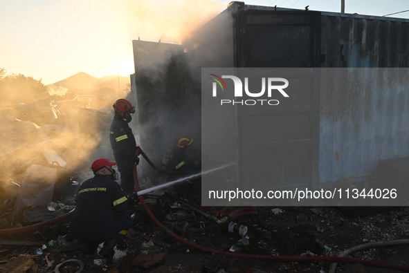 Firefighters are dropping water to extinguish a fire inside a container in Koropi near Athens, Greece, on June 19, 2024. 