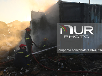 Firefighters are dropping water to extinguish a fire inside a container in Koropi near Athens, Greece, on June 19, 2024. (