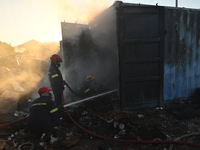 Firefighters are dropping water to extinguish a fire inside a container in Koropi near Athens, Greece, on June 19, 2024. (