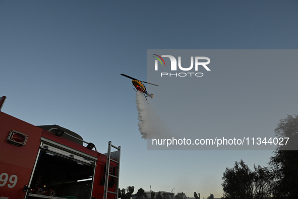 A firefighting helicopter is dropping water to extinguish a wildfire in Koropi near Athens, Greece, on June 19, 2024. 